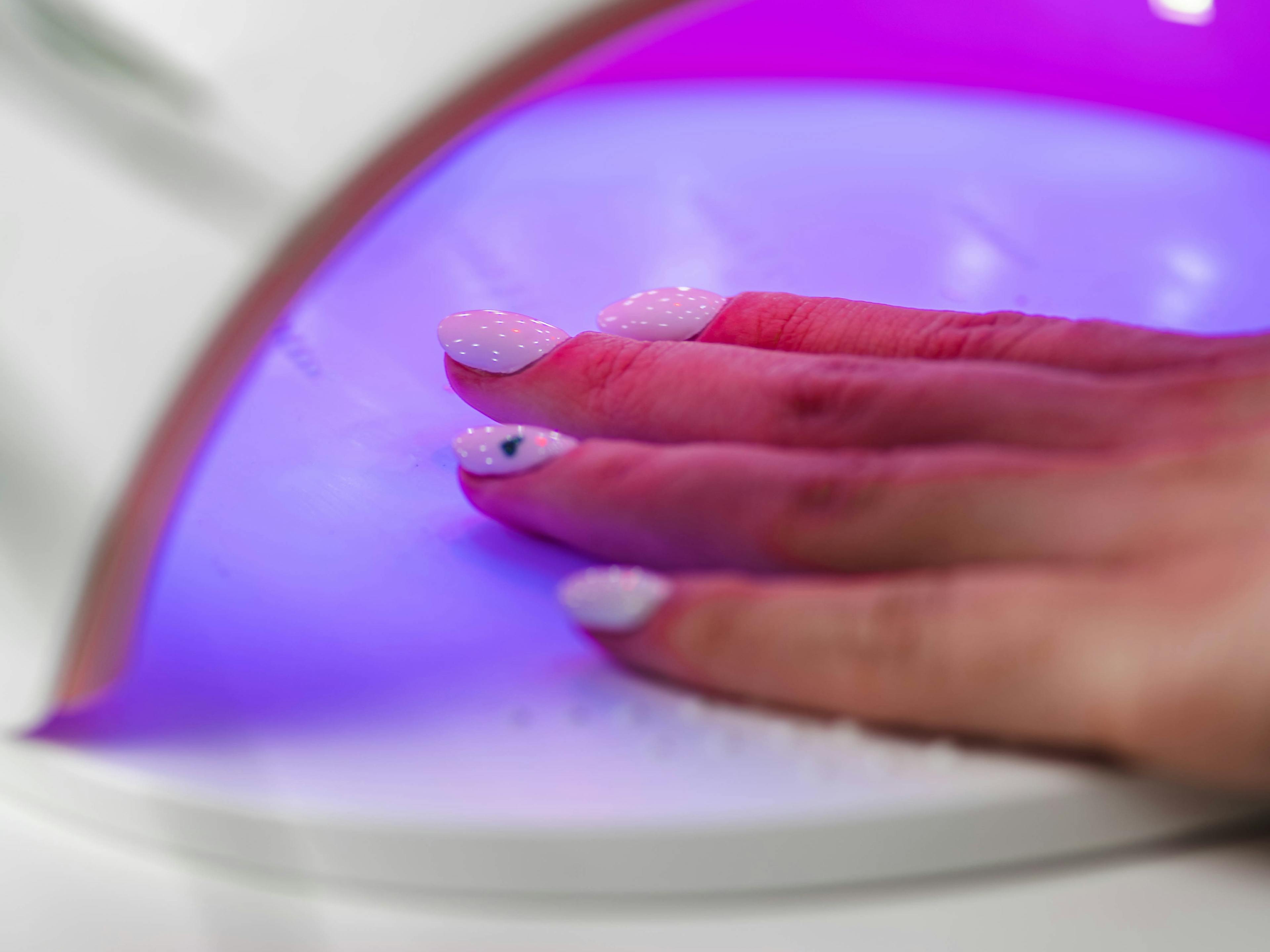 utwardzanie wartwy lakieru pod lampą UV podczas manicure hybrydowego zbliżenie