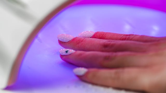 utwardzanie wartwy lakieru pod lampa UV podczas manicure hybrydowego zblizenie
