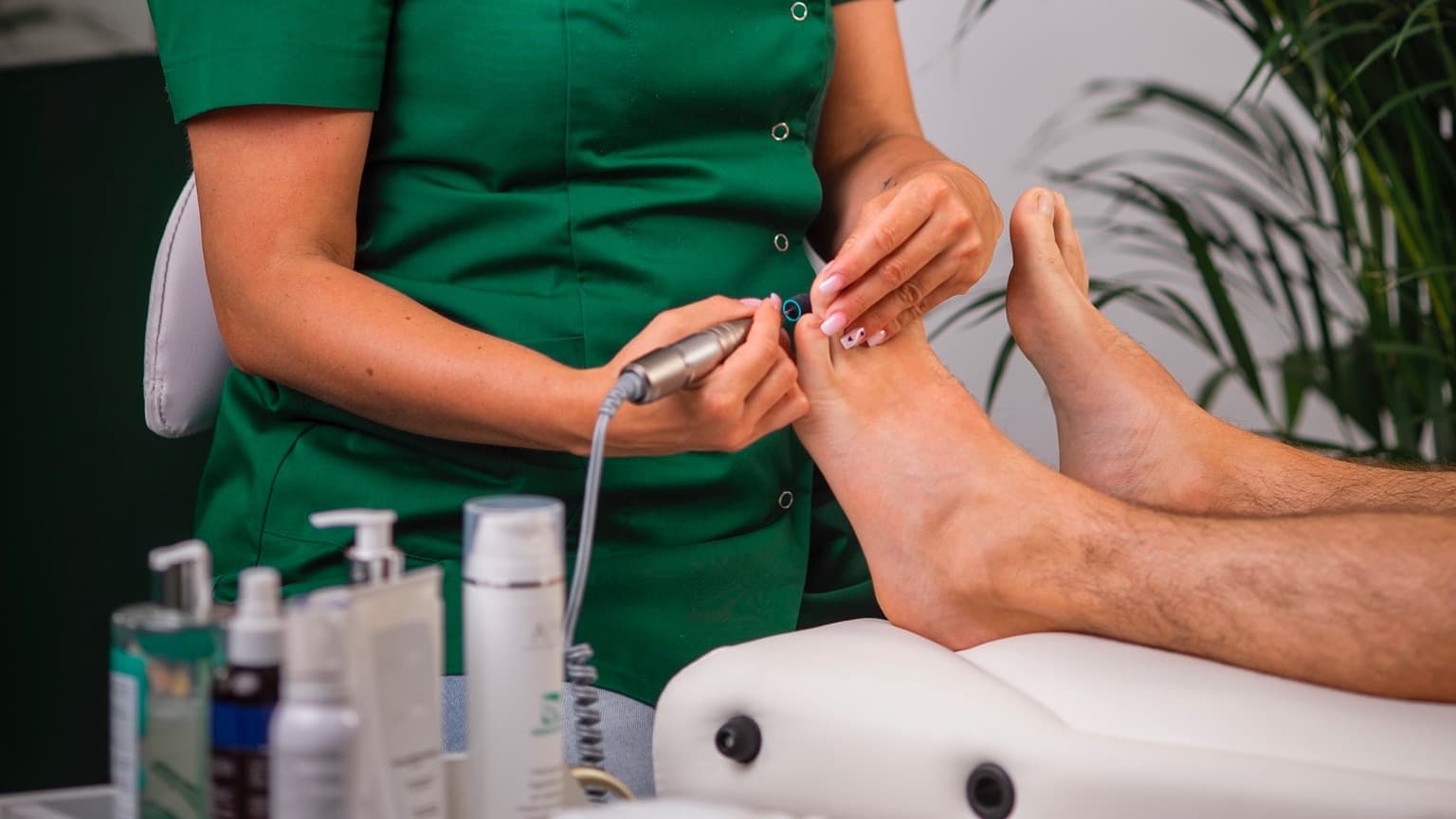 pogolog opracowuje stopy frezarka w trakcie zabiegu pedicure w salonie kosmetycznym Health and beauty w Krakowie