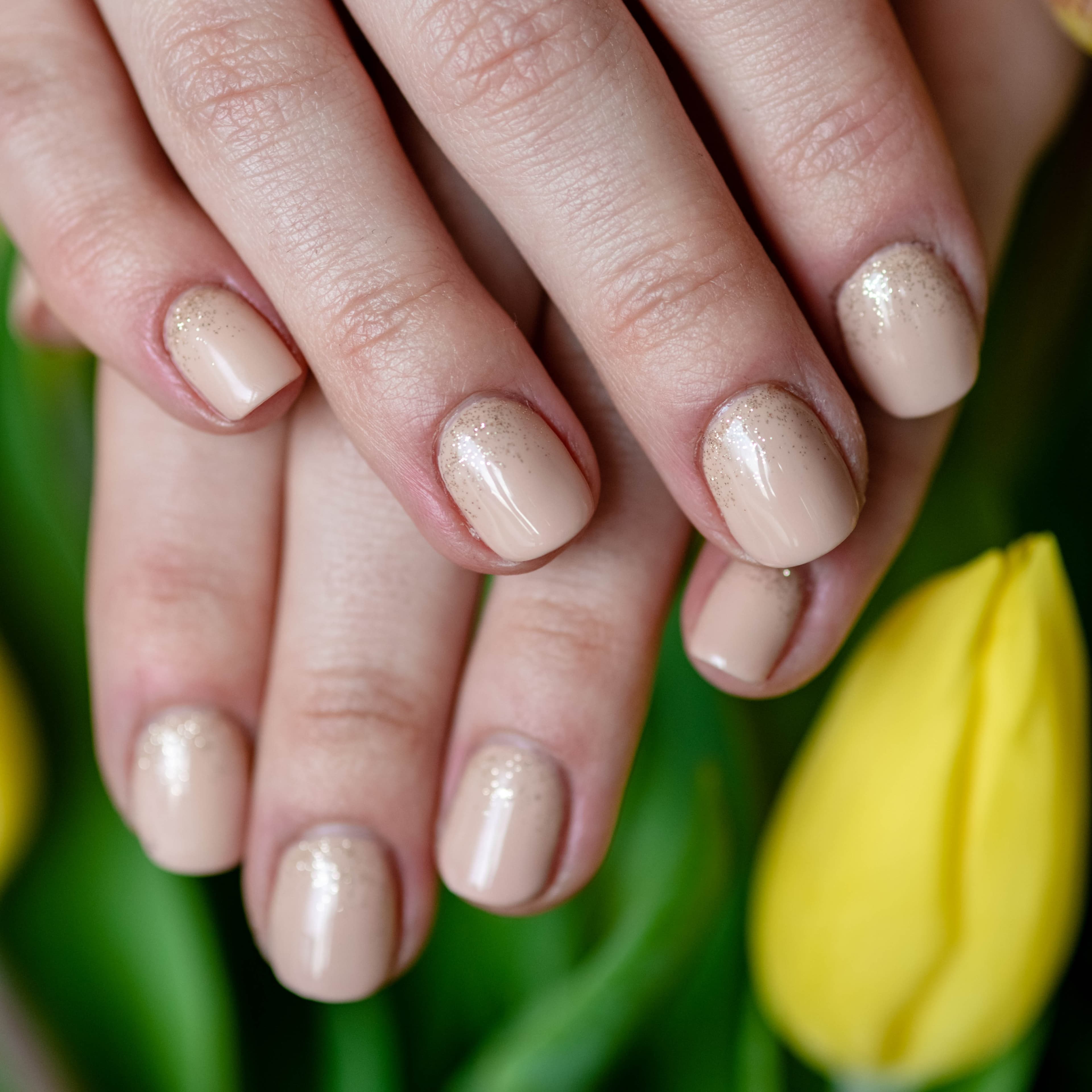 efekt manicure hybrydowego z brokatem na tle kwiatów w salonie w Krakowie
