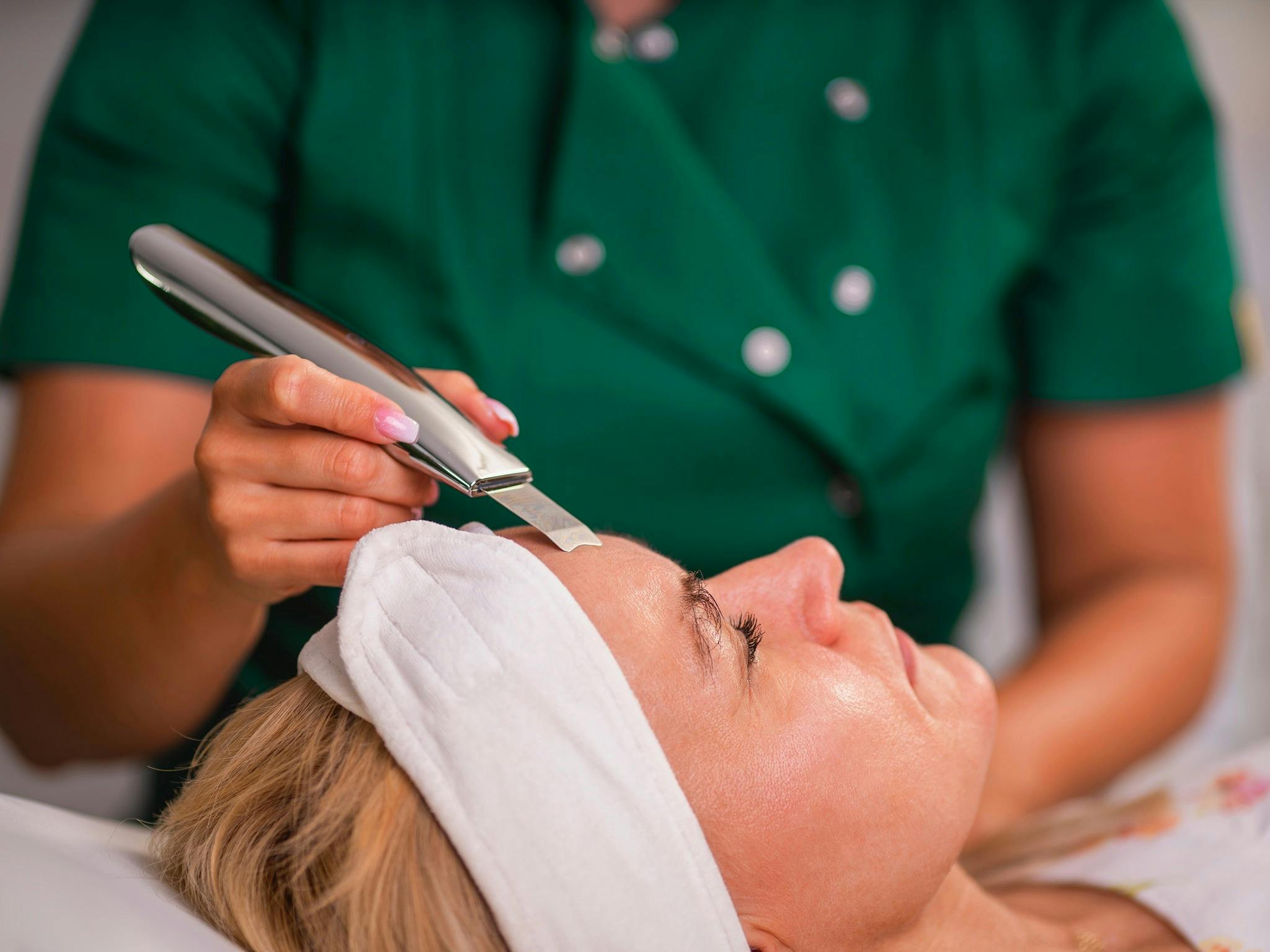 kosmetyczka w trakcie oczyszczania twarzy zabiegiem peeling kawitacyjny w salonie kosmetycznym Health and beauty w Krakowie